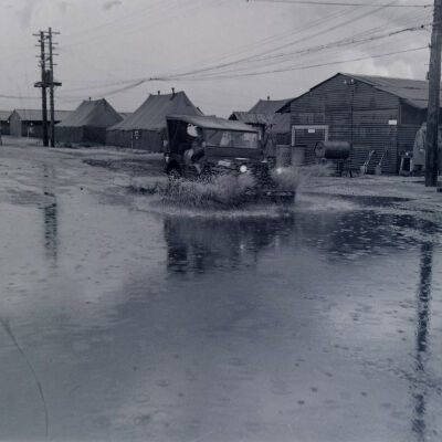 Jeep travelling a flooded road through camp
