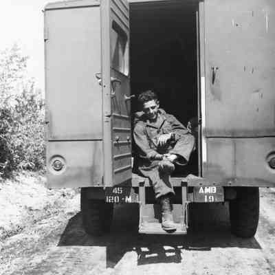 Soldier examining his foot while sitting in an ambulance