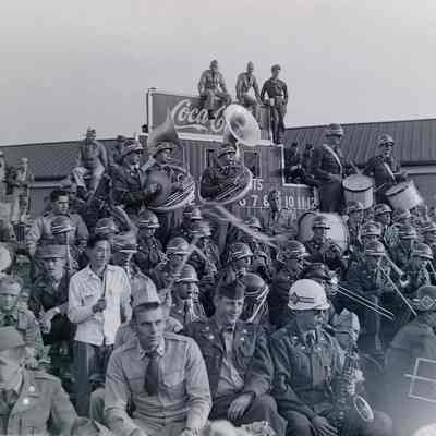 Soldiers and band members gathered around scoreboard