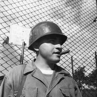 Soldier in front of a fence with cigar