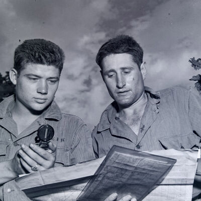 Two soldiers using a compass and map