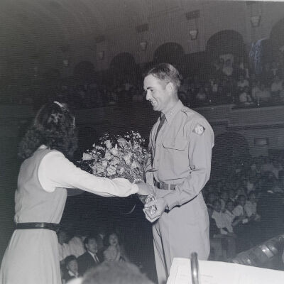 Woman presenting an officer with flowers in a large theater
