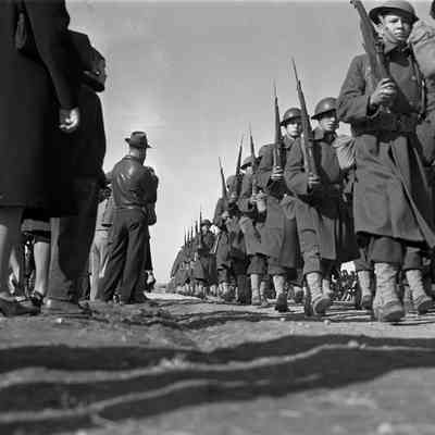 Civilians watch soldiers on a road march