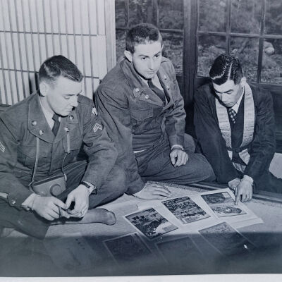 Two soldiers viewing artwork with a Japanese man
