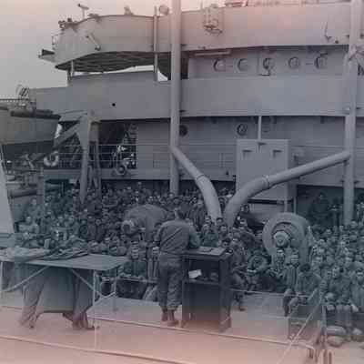 Large group of soldiers listening to a speaker onboard a ship