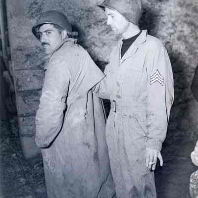 45th Soldier looks at hole in raincoat, torn by Shrapnel