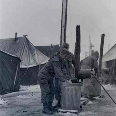 Soldiers washing mess tins at outdoor wash station