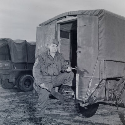 Soldier standing behind a trailer-mounted hut