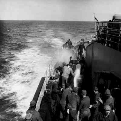 Soldiers hosing each other down on deck of a ship