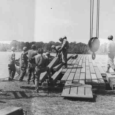 Soldiers constructing pontoon bridge deck