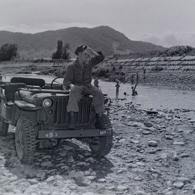 Soldier with jeep next to a swimming hole
