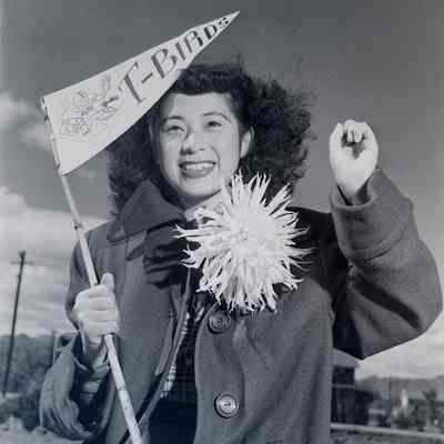 Sally Tomarikawa cheering and holding a "T-Birds" pennant