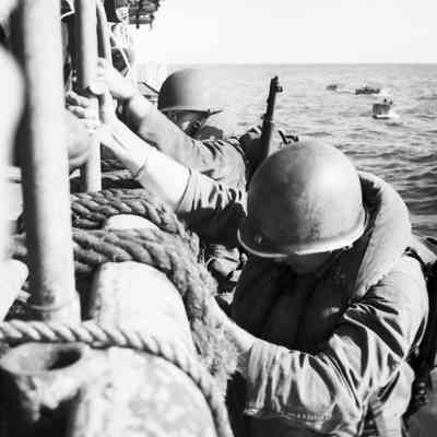 Soldiers climbing down nets into landing craft