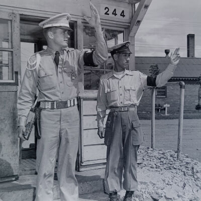 Military Police and Japanese police directing traffic and a camp gate