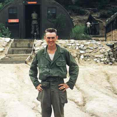 Soldier standing in front of Quonset huts