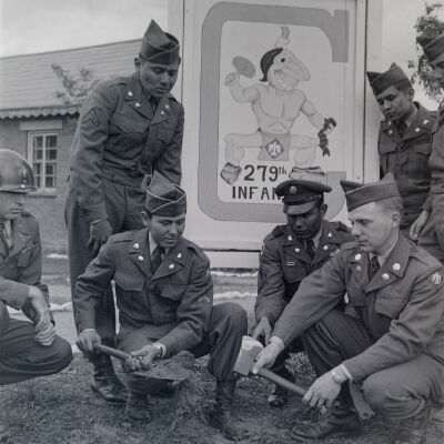 Soldiers bury a hatchet in front of sign