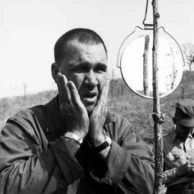 Soldier looking at himself in a field mirror