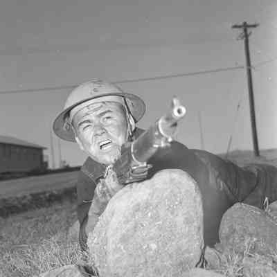 Soldier posed behind a rock with his rifle