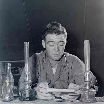 Soldier reading by oil lamps