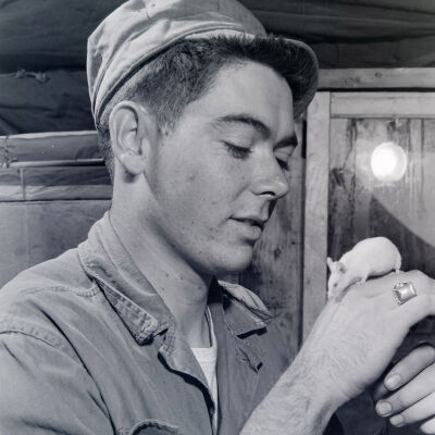 Soldier examining mouse on his hand