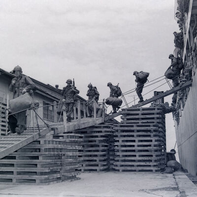 Soldiers with duffel bags and weapons coming down gangway from ship