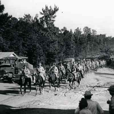 Soldiers on horseback and truck marching down road