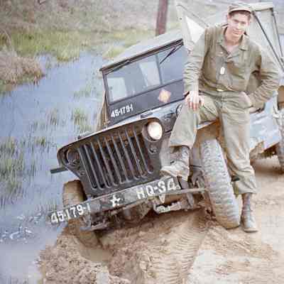 Soldier sitting on a jeep stuck in the mud
