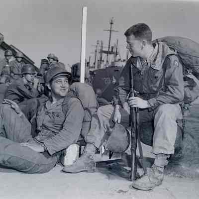 Soldiers with field gear lounging on a dock