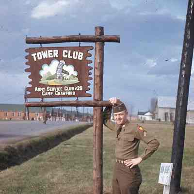 Soldier posing next to "Tower Club" sign