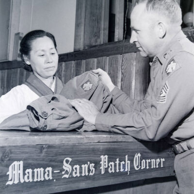 Soldier handing his uniforms to a Japanese woman over a counter