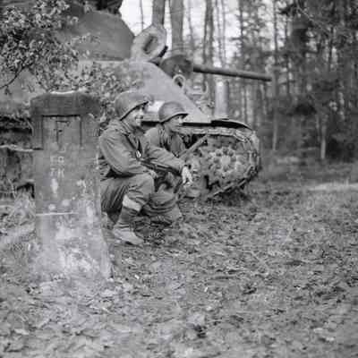 Soldiers kneel between border post and tank