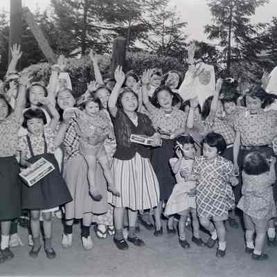 Japanese children and nuns with candy waving to the camera