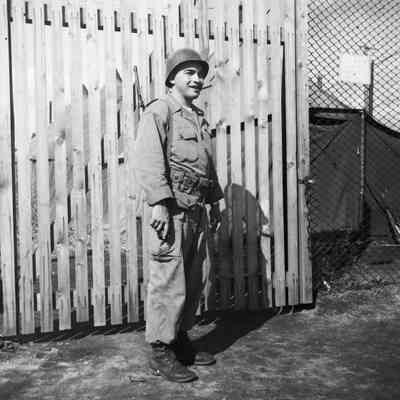 Soldier in front of a fence with cigar