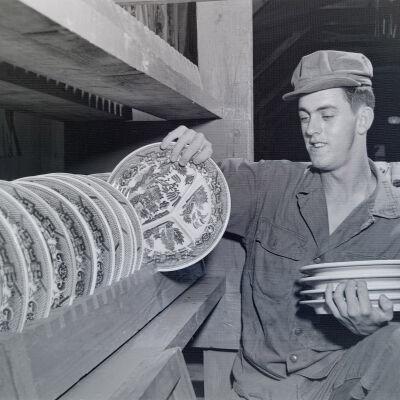 Soldier stacking dishware in mess hall