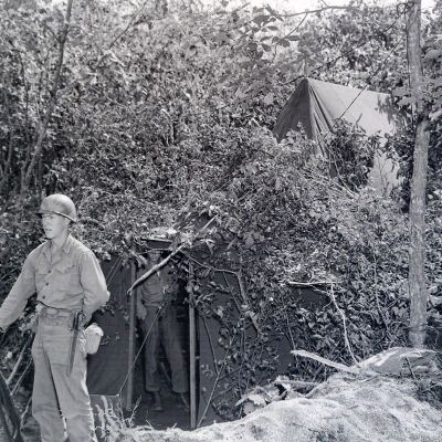 Soldier on guard duty in front of a camouflaged tent