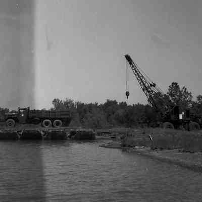 Truck parked on pontoon bridge section with crane