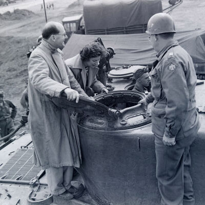 Officer showing two civilians the inside of a tank