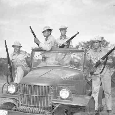Soldiers posed on a truck with rifles at the ready