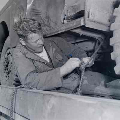 Soldier tying down a truck on a cargo pallet