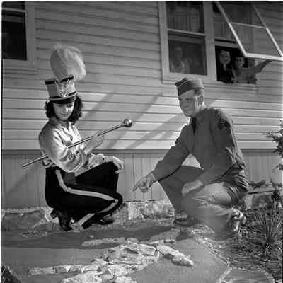 Soldier and a majorette viewing a unit insignia