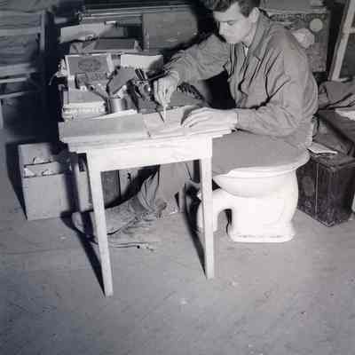 Soldier using a toilet seat as a chair