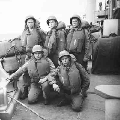 Soldiers on deck wearing life vests and helmets