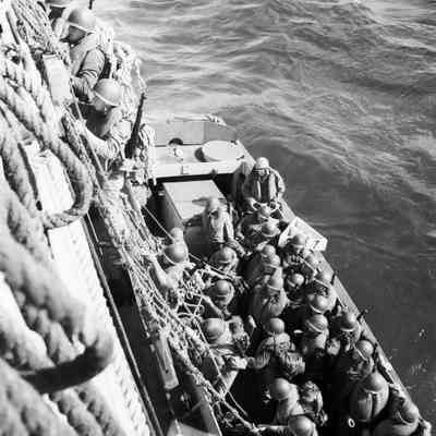 Soldiers climbing nets from ship to landing craft