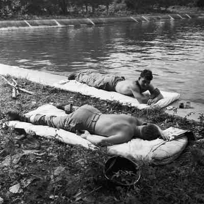 Soldiers relaxing on mattresses at the edge of a lake