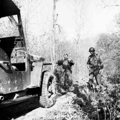 Soldiers guiding a Jeep over wooden planking