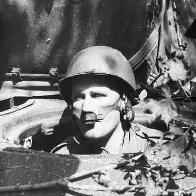 Tank crewman wearing intercom mic looking out of hatch