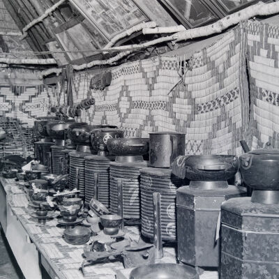 Ainu man in front of crafts and pottery