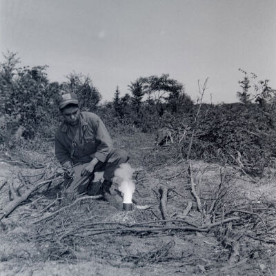 Soldier burning a very flammable substance in a tin can