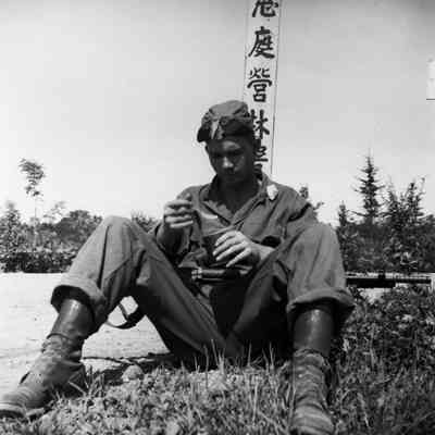 Soldier with his weapon eating c-rations