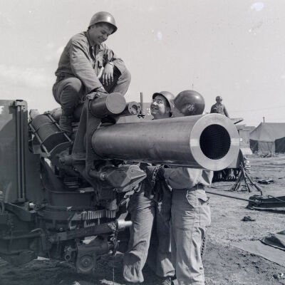 Group of soldiers looking over a 155mm howitzer